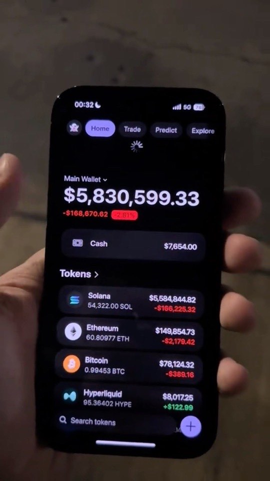 A hand holding a phone showing a crypto wallet screen with a balance above five million dollars.