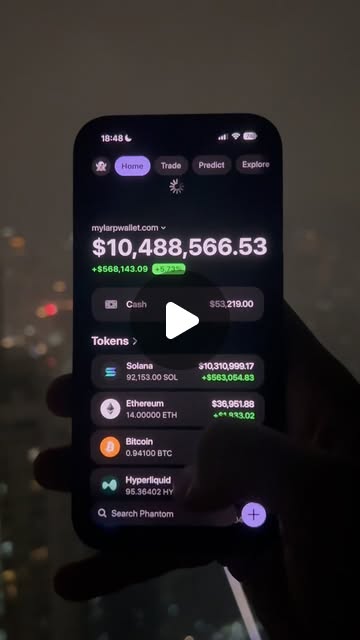 A phone filmed at night against a blurred skyline, showing a wallet balance of $10,488,566.53.