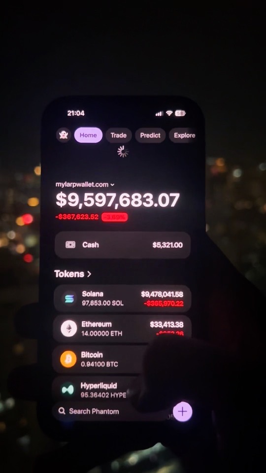 A phone held up at night against city lights, showing a wallet balance of $9,597,683.07 above its token list.